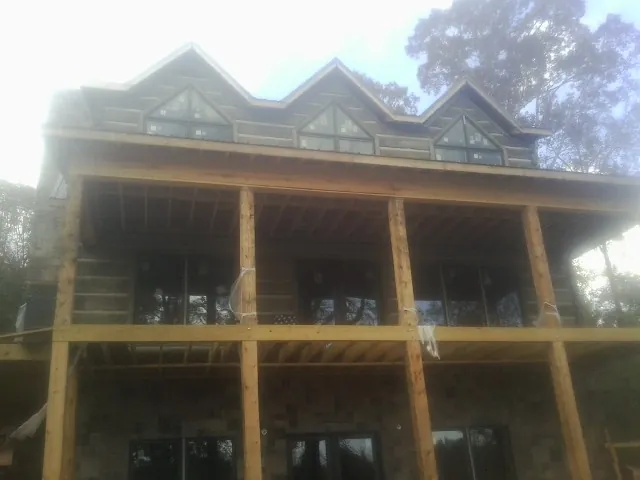 Dormers and porch framing on a large log home under construction — Roof Coating work by our crew in Sheldon